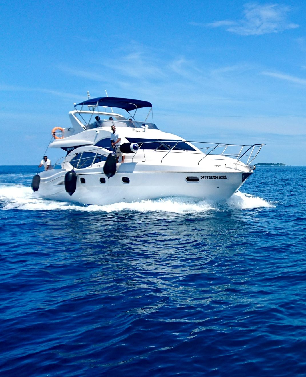 Un yacht blanc navigue sur une mer bleue sous un ciel ensoleillé.