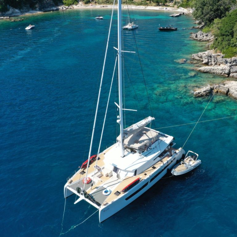 Un catamaran ancré dans une eau turquoise, entouré de petites îles et bateaux.