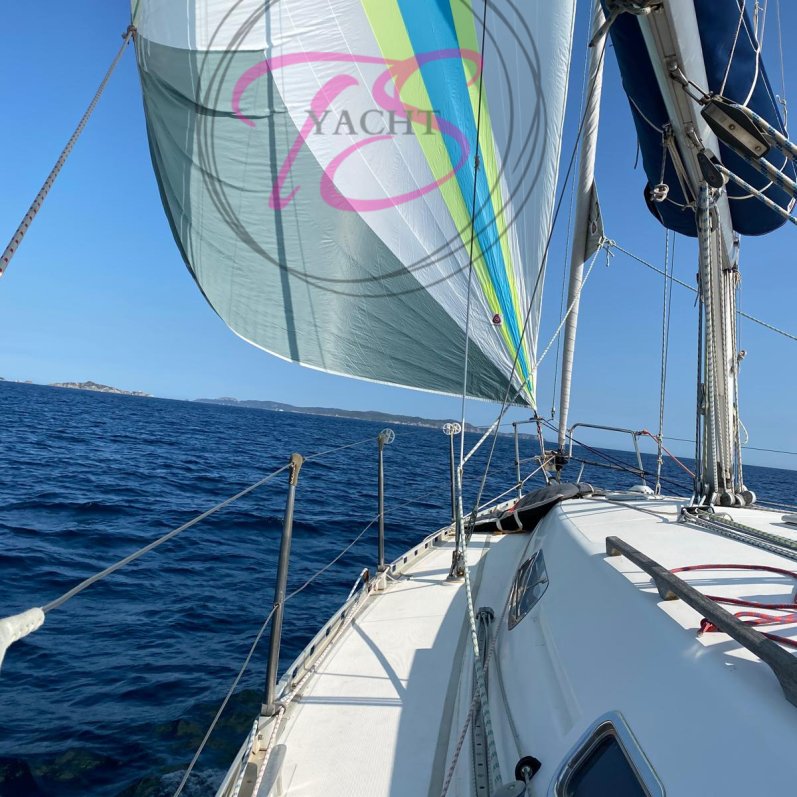 Voile colorée sur un voilier naviguant sur une mer calme.